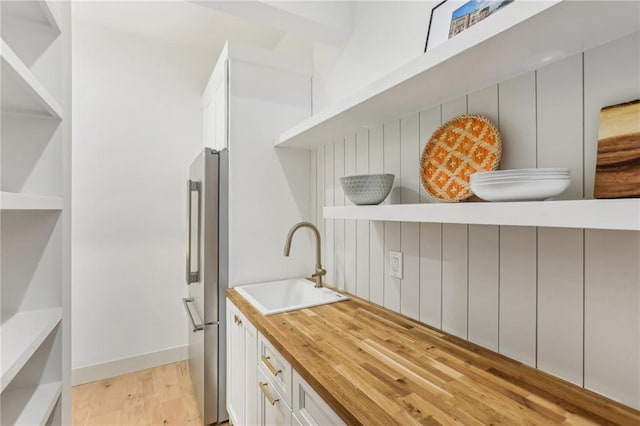 kitchen with white cabinets, high end refrigerator, light hardwood / wood-style floors, and sink