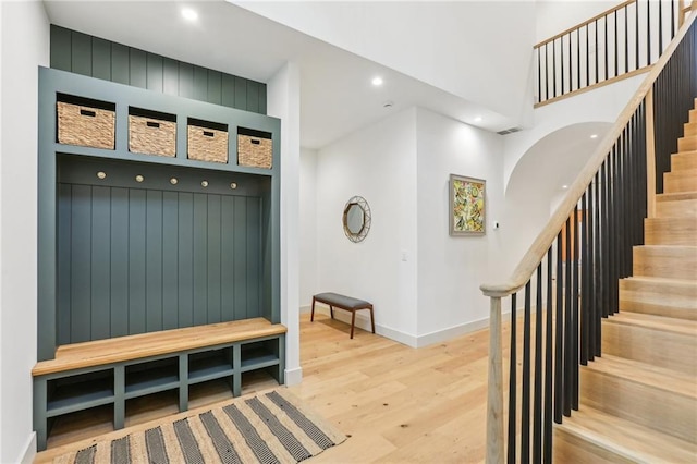 mudroom with light hardwood / wood-style flooring and a towering ceiling