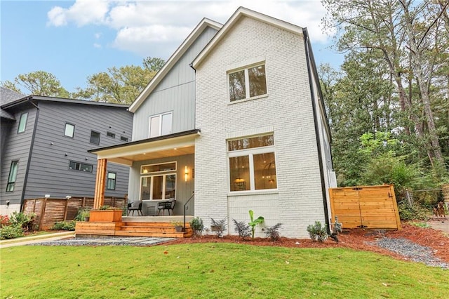 rear view of property with covered porch and a yard