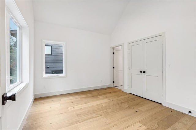 unfurnished bedroom with high vaulted ceiling and light hardwood / wood-style floors