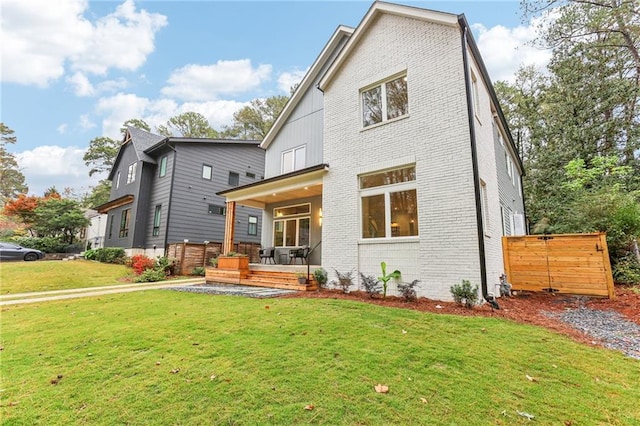 back of property featuring a lawn and covered porch