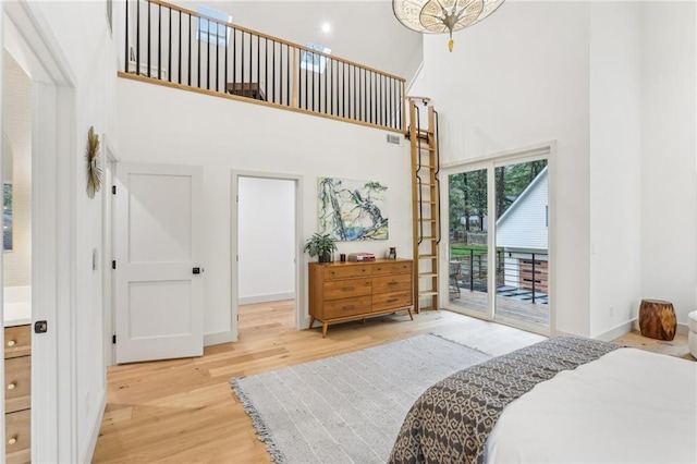 bedroom with access to outside, a high ceiling, and hardwood / wood-style flooring