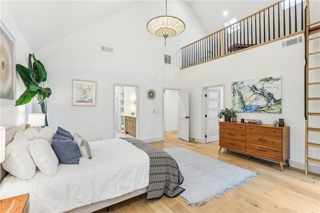 bedroom with light wood-type flooring, connected bathroom, and high vaulted ceiling