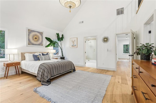 bedroom with ensuite bath, light hardwood / wood-style flooring, and high vaulted ceiling