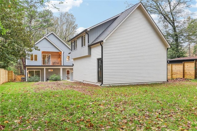 rear view of house with a lawn and a balcony