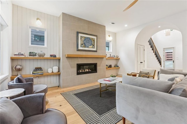 living room with wood walls, light hardwood / wood-style flooring, and a tiled fireplace