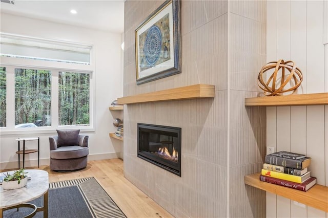 living area featuring a tile fireplace and light hardwood / wood-style floors