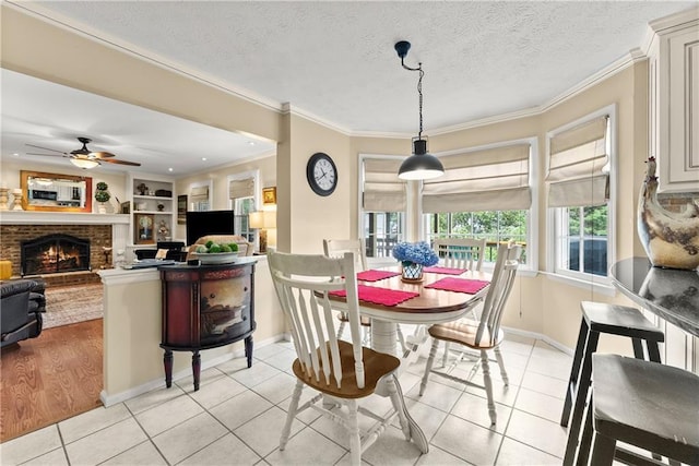 1083 Wash Lee Dr SW, Lilburn, GA 30047 - dining room featuring light tile patterned floors, ornamental molding, a ceiling fan, a brick fireplace, and a textured ceiling