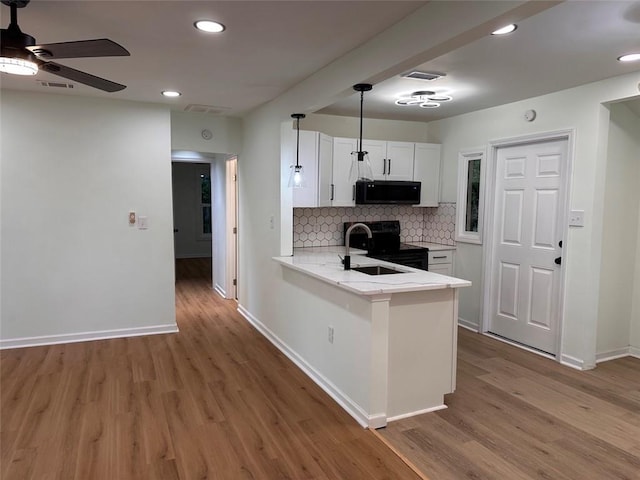 kitchen with tasteful backsplash, white cabinets, hardwood / wood-style floors, range with electric stovetop, and kitchen peninsula