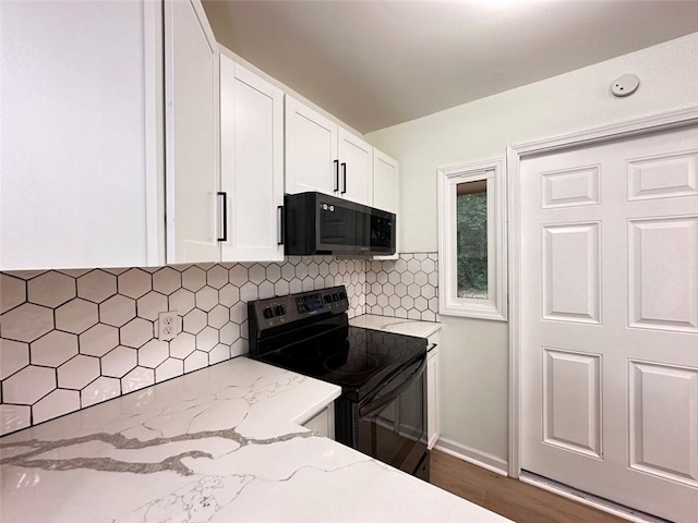 kitchen with white cabinets, dark hardwood / wood-style floors, black appliances, light stone countertops, and decorative backsplash