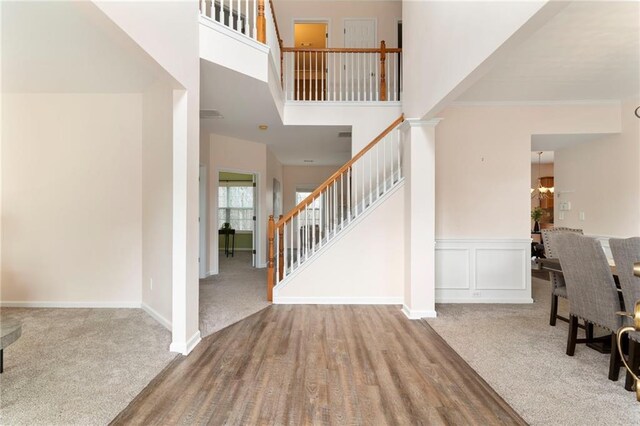 entrance foyer with ornamental molding, a high ceiling, and carpet flooring