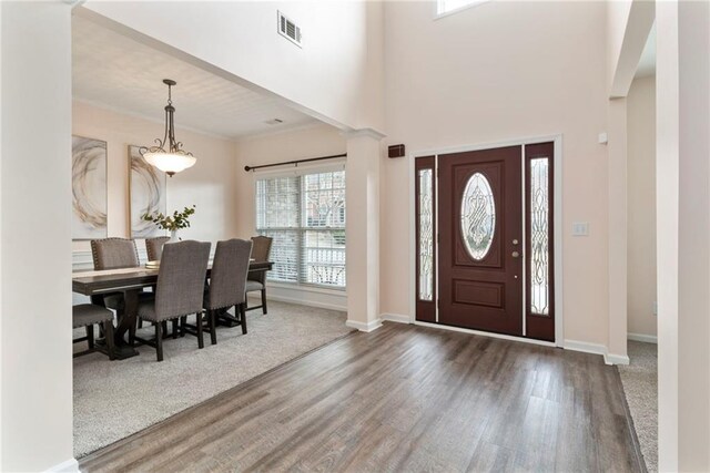 entrance foyer featuring crown molding, a towering ceiling, dark hardwood / wood-style flooring, and decorative columns