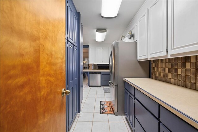 kitchen with tasteful backsplash, light countertops, white cabinetry, stainless steel dishwasher, and light tile patterned flooring