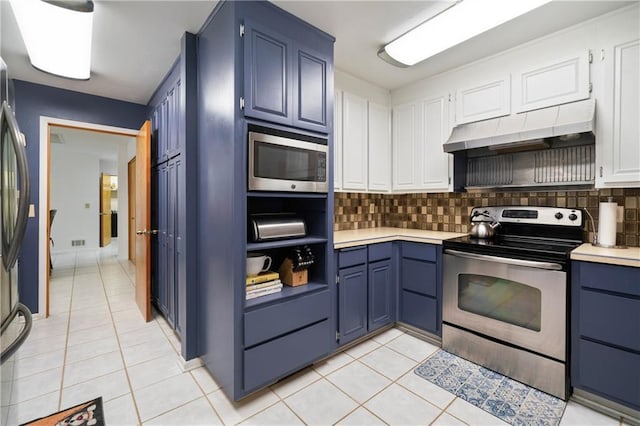 kitchen featuring appliances with stainless steel finishes, blue cabinets, under cabinet range hood, and light tile patterned floors
