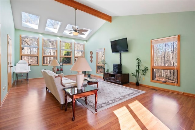 living area with vaulted ceiling with skylight, wood finished floors, and baseboards