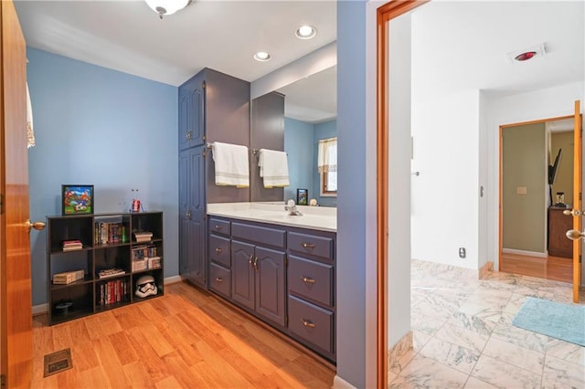 bathroom with visible vents, wood finished floors, vanity, and baseboards