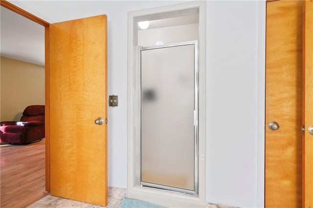 full bathroom featuring a shower stall and wood finished floors