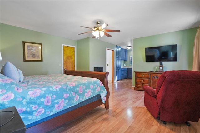bedroom featuring ceiling fan, light wood finished floors, and connected bathroom