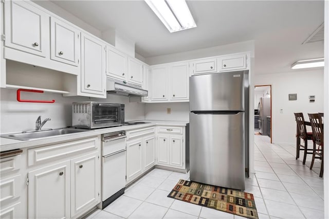 kitchen featuring light tile patterned floors, a sink, freestanding refrigerator, and under cabinet range hood