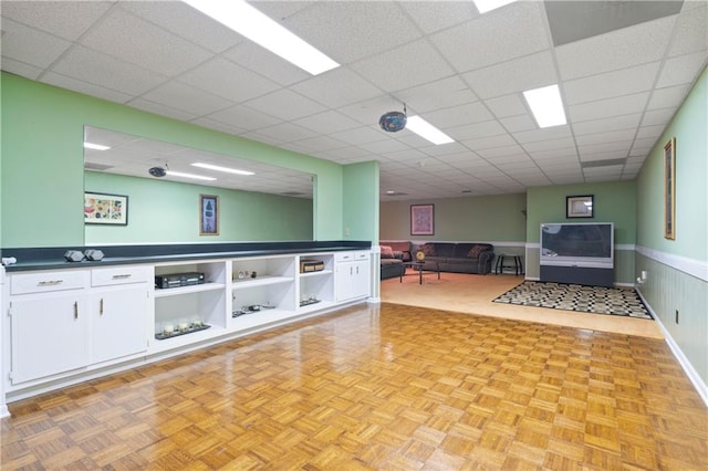 interior space featuring a paneled ceiling and a wainscoted wall