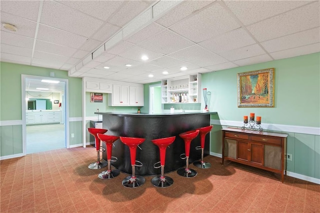 bar with a dry bar, baseboards, a paneled ceiling, and recessed lighting