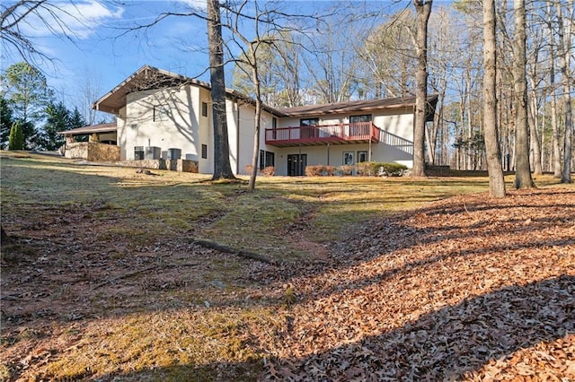 rear view of property featuring a lawn, a deck, and stucco siding