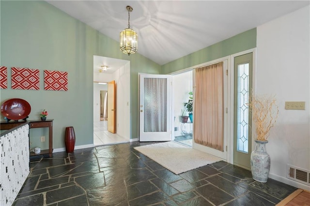 entryway featuring lofted ceiling, stone tile floors, visible vents, baseboards, and an inviting chandelier