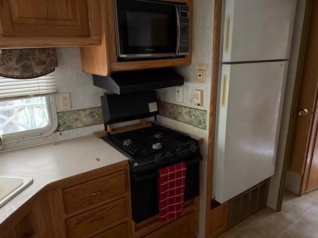 kitchen featuring light countertops, black appliances, brown cabinets, and under cabinet range hood