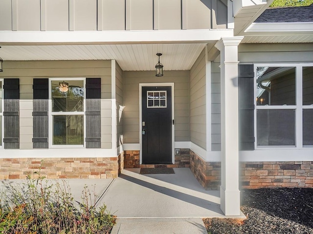 property entrance featuring board and batten siding, stone siding, and covered porch