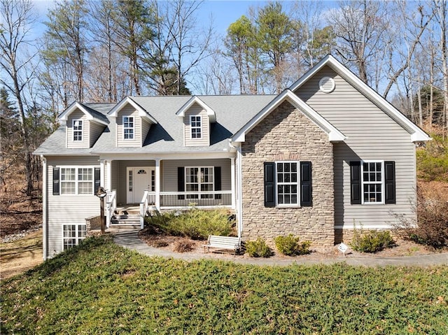 cape cod house featuring stone siding, a porch, and a front yard