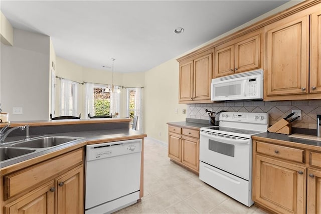 kitchen with white appliances, tasteful backsplash, dark countertops, hanging light fixtures, and a sink