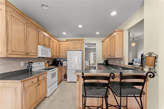 kitchen featuring white appliances, tasteful backsplash, dark countertops, a breakfast bar area, and light brown cabinetry