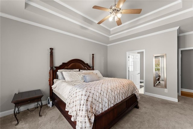 carpeted bedroom with ornamental molding, a tray ceiling, baseboards, and a ceiling fan