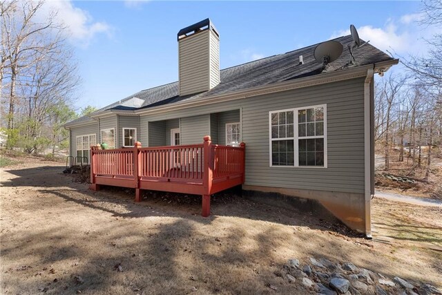 rear view of house featuring a chimney and a wooden deck