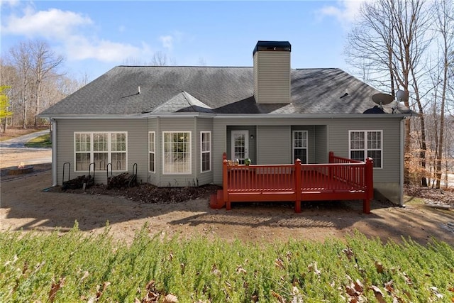 back of property featuring roof with shingles, a chimney, and a wooden deck