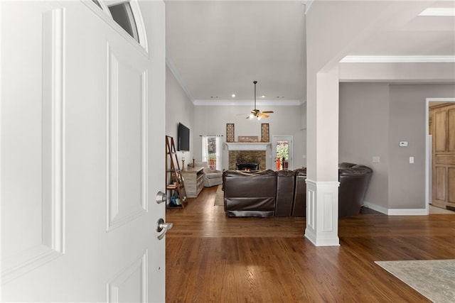 entrance foyer with a fireplace, wood finished floors, a ceiling fan, and crown molding
