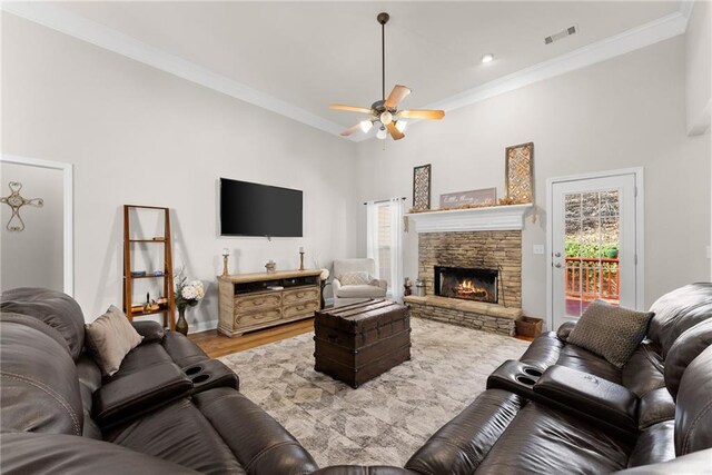 living room with light wood-type flooring, a fireplace, visible vents, and crown molding