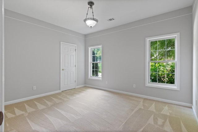 spare room with light carpet, baseboards, and visible vents