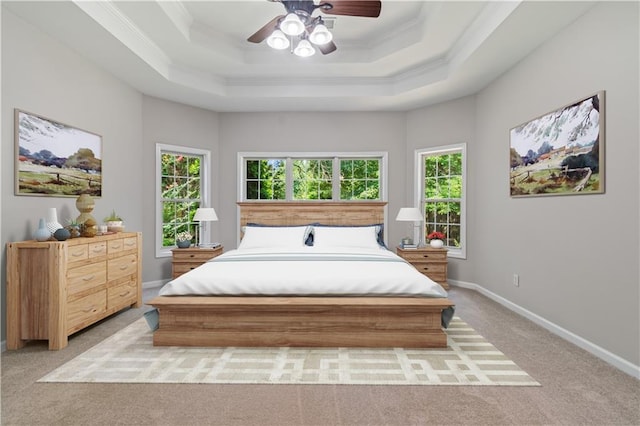 bedroom with ornamental molding, a tray ceiling, light colored carpet, and baseboards