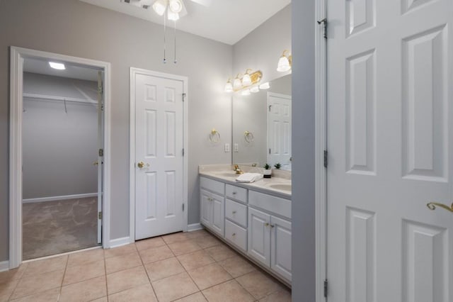 bathroom featuring a sink, baseboards, a spacious closet, tile patterned floors, and double vanity