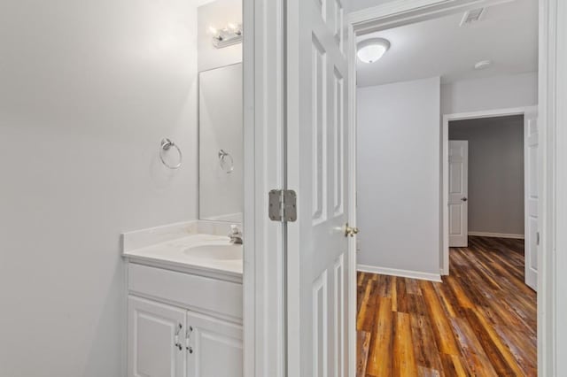 bathroom featuring baseboards, visible vents, wood finished floors, and vanity