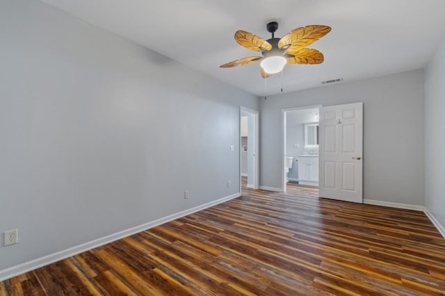 unfurnished bedroom featuring baseboards, visible vents, ceiling fan, dark wood-type flooring, and ensuite bathroom