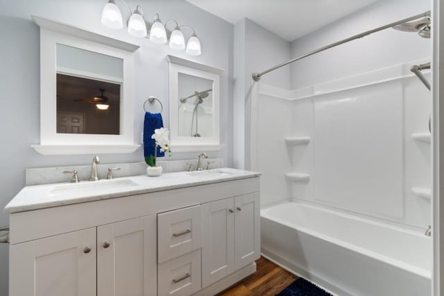 bathroom with double vanity, wood finished floors, a sink, and shower / tub combination