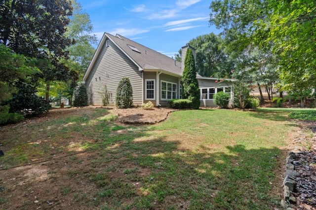 back of property with a chimney and a yard