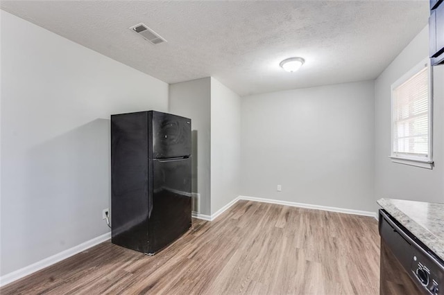 interior space featuring light wood finished floors, visible vents, baseboards, and black appliances
