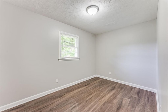 empty room featuring baseboards, a textured ceiling, and dark wood-style floors