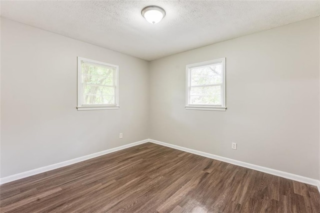 unfurnished room with dark wood-style flooring, baseboards, and a wealth of natural light