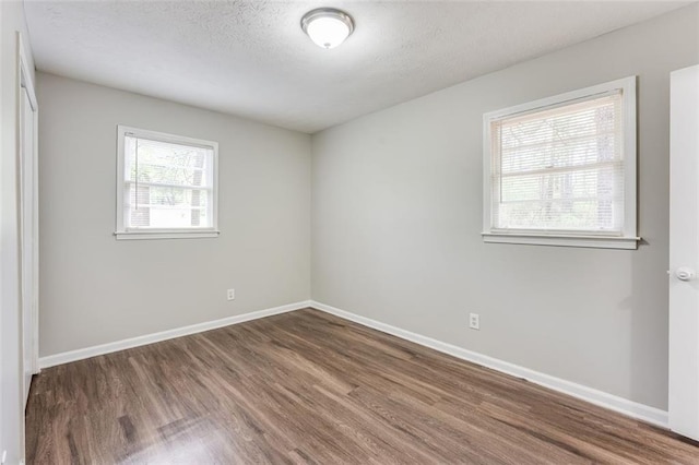 unfurnished room featuring a textured ceiling, wood finished floors, and baseboards