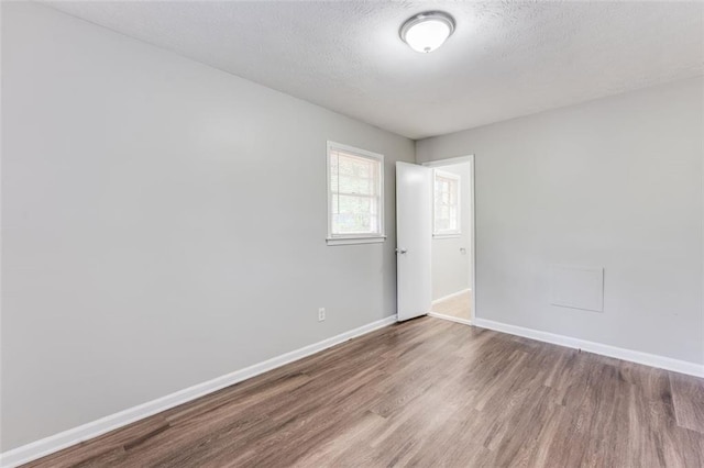 spare room with baseboards, a textured ceiling, and wood finished floors