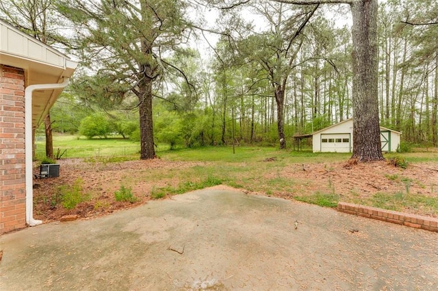 view of yard with a patio area, a detached garage, and an outdoor structure